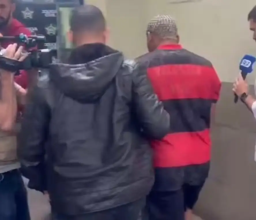 Suspeito ( de camisa listrada) ao chegar preso na Delegacia de Homicídios da Capital