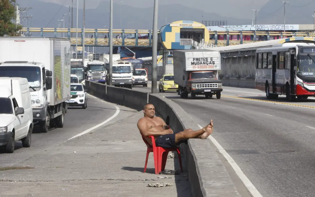 Paulo Vitor pegou uma cadeira e decidiu ficar exposto ao sol na Avenida Brasil