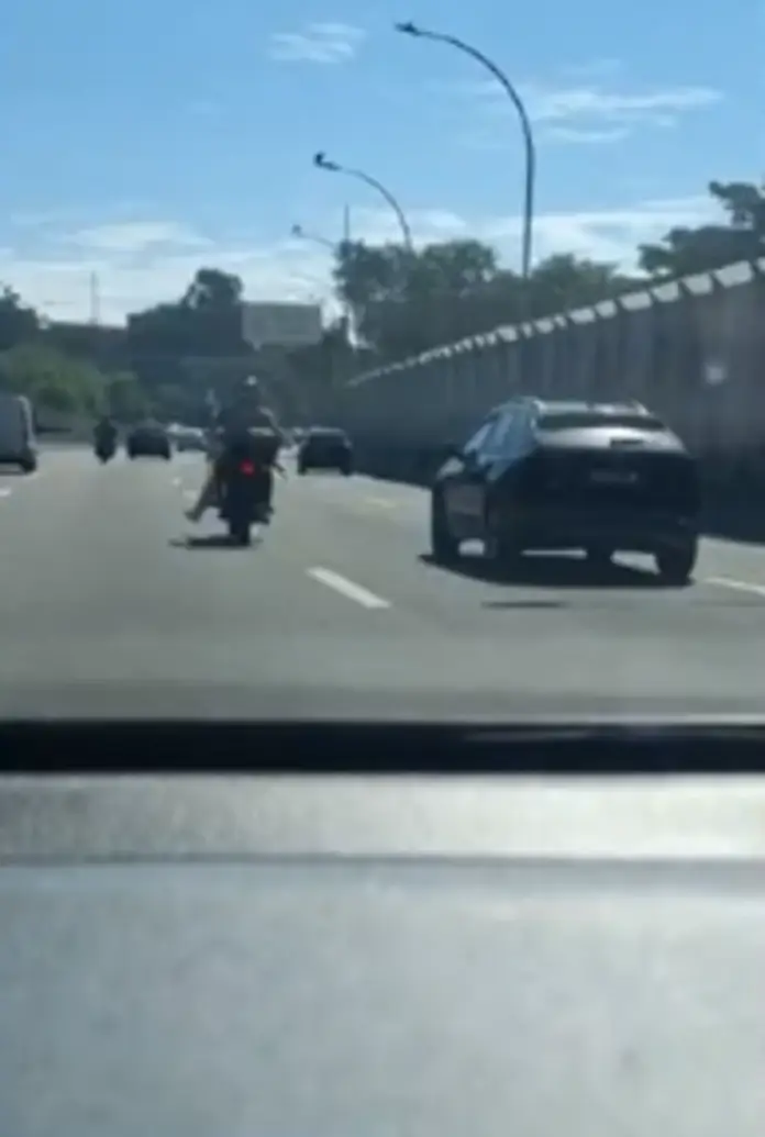 Motociclista com perna engessada troca marcha com vassoura
