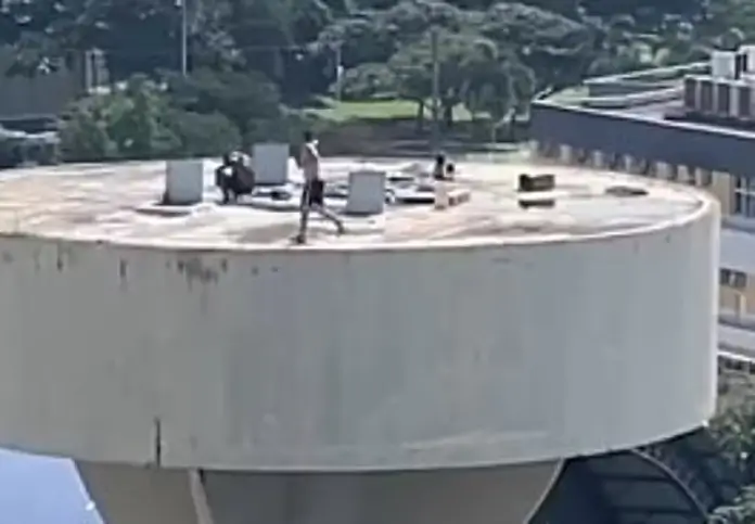 homem em risco ao correr no topo de caixa d’águ