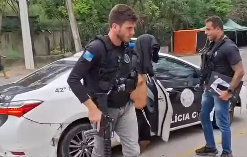 Professor, com camisa na cabeça, é levado para a 42ª DP (Recreio) após ser preso