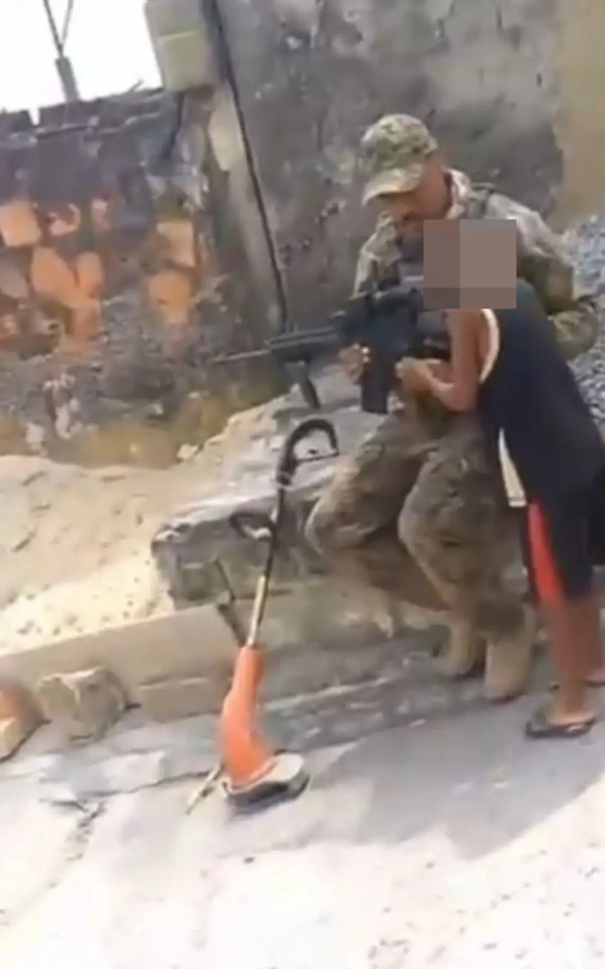 policial do Bope permitindo que uma criança segure fuzil