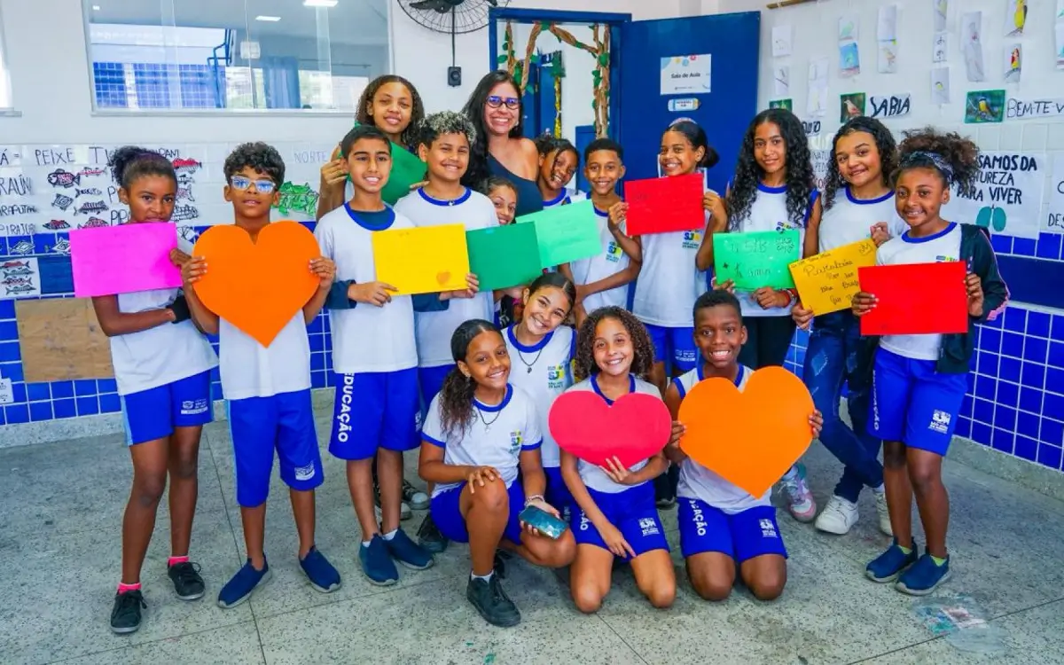 O Prêmio Magda Soares em Meriti foi conquistado pelo Complexo Educacional da Vila São João, em São João de Meriti, na Baixada Fluminense. A unidade venceu a categoria “Recomposição de Aprendizagens” na etapa final da premiação promovida pela Secretaria de Estado de Educação do Rio de Janeiro. O reconhecimento veio por meio do projeto “Percurso literário: conhecendo Eva Furnari, Daniel Munduruku e Sônia Rosa”, idealizado e aplicado pela professora Letícia Graciano ao longo do ano letivo na turma 51B. A proposta pedagógica teve como foco o estímulo à leitura, à escrita e ao desenvolvimento do pensamento crítico dos alunos. Durante o percurso, os estudantes participaram de atividades práticas e interativas, como a produção de tintas naturais com urucum, confecção de cartazes coletivos, leituras individuais e em grupo e a criação de um clube do livro dentro da sala de aula. A iniciativa resultou na leitura de mais de 30 obras literárias pelos alunos ao longo do ano. A professora Letícia Graciano celebrou o prêmio e destacou o envolvimento da turma no processo de aprendizagem. “Esse prêmio mostra o reconhecimento pela minha prática pedagógica, por tudo o que acredito e por tudo aquilo que desempenhei durante o ano. A turma é reflexo do professor e o professor é reflexo da turma. Só pude desempenhar o trabalho porque tive uma turma que me abraçou e andou junto comigo”, afirmou. A secretária municipal de Educação, Ciência e Tecnologia, Eneila Lucas, também comemorou a conquista e ressaltou o impacto do projeto na rede pública. “Esse reconhecimento mostra a capacidade da nossa rede de inovar e transformar o aprendizado dos alunos. Projetos como o desenvolvido pela professora Letícia fortalecem toda a comunidade escolar e elevam o nível da educação de Meriti”, destacou. Os alunos relataram mudanças no interesse pela leitura e nas atividades em sala. “Aprendemos muito com as atividades e os livros que ela nos trouxe, e também gostamos muito de fazer as pinturas que estão espalhadas pela sala”, contou a estudante Maysa Lima. Já Pedro Henrique destacou a integração entre disciplinas. “Um dos livros que mais gostei foi ‘Os problemas da família Gorgonzola’, que tem questões matemáticas e me ajudou a gostar de matemática e português”, disse. O Prêmio Magda Soares reconhece práticas pedagógicas inovadoras voltadas à alfabetização, recomposição de aprendizagens e incentivo à leitura. A iniciativa valoriza projetos com resultados concretos e contribuições significativas para o avanço da educação pública em todo o estado do Rio de Janeiro.
