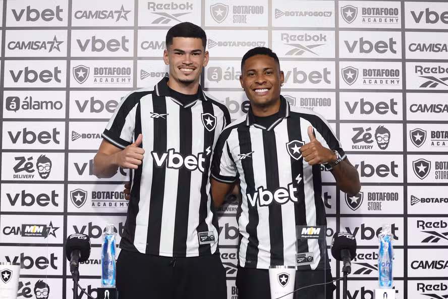 Os reforços do Botafogo foram oficialmente apresentados nesta terça-feira (7), no Estádio Nilton Santos, e já começam a se adaptar ao novo ambiente. O lateral-esquerdo Caio Roque e o zagueiro Anthony chegaram ao clube cercados de expectativa e destacaram o apoio recebido por jogadores mais experientes do elenco. Caio Roque, de 24 anos, já teve a oportunidade de estrear com a camisa alvinegra e participou diretamente de um momento importante ao dar uma assistência na vitória sobre o Vasco. Disputando posição com atletas consolidados, o lateral valorizou o aprendizado no dia a dia com nomes de peso dentro do grupo. — O contato com o Telles e Marçal foi interessante. São caras que ganharam aqui e fora do Botafogo. Quando cheguei aqui, o Telles me deixou muito tranquilo. Nas duas partidas que entrei ele me deu muitas dicas, é um cara que me espelho muito. Fico feliz de dividir o campo com ele, é um cara que vou aprender mais — disse o lateral. — Fiquei feliz com o clássico, com a assistência. Fiquei feliz ao entrar, o Telles me ajudou bastante. Quando soube que ia sair, me deu todas as alternativas que eu podia fazer no campo para pode me sair bem e deu tudo certo — completou. Já Anthony, de 20 anos, ainda aguarda a oportunidade de fazer sua estreia pelo clube. Contratado após passagem pelo Goiás, o zagueiro assinou contrato de longo prazo e demonstrou confiança no processo de adaptação, mesmo diante da concorrência por posição. — As expectativas são grandes, são as melhores possíveis. Tenho muito a mostrar dentro de campo. Tudo tem a hora certa, vai chegar o momento certo. A hora que o Franclim achar que vai ser o momento, vou estar preparado. O defensor também destacou a importância de conviver com jogadores experientes, ressaltando o aprendizado diário e a chance de evolução dentro do elenco. — Muito gratificante estar junto desses caras, tenho muito a aprender com eles. Muito feliz por tudo que estou vivendo — destacou o jogador — Zagueiro canhoto é uma carência no futebol, estou aqui para somar. Quando eu tiver as oportunidades, vou mostrar. Mesmo com a forte concorrência no setor defensivo, a característica de atuar pelo lado esquerdo pode representar uma vantagem estratégica para o jovem atleta ao longo da temporada. No Botafogo, a chegada de novos jogadores reforça não apenas o elenco, mas também a competitividade interna, criando um ambiente propício para evolução e busca por espaço dentro do time.