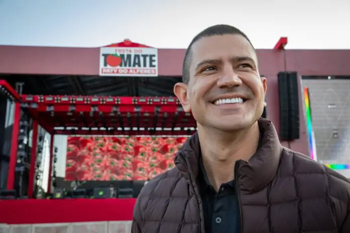 Douglas Ruas participou da abertura da 36ª edição da Festa do Tomate, em Paty do Alferes, no Centro-Sul Fluminense. Presidente da Assembleia Legislativa do Estado do Rio de Janeiro, o deputado estadual esteve no Parque de Exposições Amaury Pullig, em Avelar, onde acontece um dos eventos mais tradicionais da região. A Festa do Tomate é considerada o maior evento de Paty do Alferes e tem papel importante na movimentação da economia local. A edição de 2026 reúne atrações musicais, valoriza a produção agrícola e deve atrair milhares de visitantes ao município. Durante a abertura, Douglas Ruas esteve ao lado do prefeito Julinho Juju, do senador Carlos Portinho e do deputado estadual Gustavo Tutuca. Em sua fala, o presidente da Alerj destacou o momento vivido pela cidade e citou ações realizadas quando esteve à frente da Secretaria de Estado das Cidades. Entre as obras mencionadas pelo deputado está a recuperação da RJ-125, rodovia considerada estratégica para moradores, visitantes e para o escoamento da produção regional. A melhoria da via foi apontada como uma das ações importantes para ampliar a segurança e a mobilidade na região. “Ouvi moradores dizendo que a rodovia está restaurada e oferecendo mais segurança. Esse reconhecimento me traz muita felicidade, porque quando melhoramos a mobilidade urbana de uma região estamos melhorando a qualidade de vida de cada um deles”, afirmou Douglas Ruas. Além da programação musical, a Festa do Tomate funciona como vitrine para Paty do Alferes. O evento impulsiona hotéis, restaurantes, comércios e serviços, além de reforçar a identidade agrícola do município. Douglas Ruas afirmou que seguirá acompanhando as demandas de Paty do Alferes junto ao Governo do Estado do Rio de Janeiro. Segundo ele, a continuidade de ações e investimentos segue como prioridade para contribuir com o desenvolvimento da cidade. Com a abertura da 36ª edição da festa, Paty do Alferes reforça sua posição como destino turístico e agrícola de destaque no interior do estado.