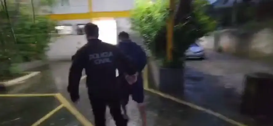 policial acompanha um suspeito preso até a delegacia